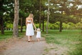 Family of little blonde girl and her middle age mother walking in the park in summer time. Childhood, single mother concept Royalty Free Stock Photo