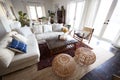 A family living room with French windows and a large comfortable corner sofa, seen in daylight, incidental people in shot