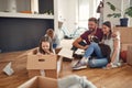 Family in living room have a fun spend time at new home. playful laughing girl sitting at cardboard box, boy rolling her playing Royalty Free Stock Photo