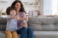 Mom and kid showing like gesture holding phone on selfie stick for video call, sit on couch at home Royalty Free Stock Photo