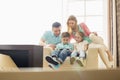 Family looking at boy playing hand-held video game at home Royalty Free Stock Photo