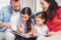 Family looking in picture book while sitting on sofa Royalty Free Stock Photo