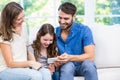 Family looking at smart phone while sitting on sofa