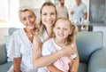 Family, love and generations with a girl, mother and grandmother sitting on a living room sofa in the home together Royalty Free Stock Photo