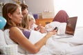 Family Lying In Bed Together Using Digital Devices Royalty Free Stock Photo