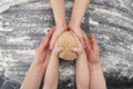 Family makes cookies in kitchen. Hands of mother and two children are holding piece of dough