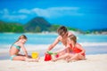 Family making sand castle at tropical white beach. Father and two girls playing with sand on tropical beach Royalty Free Stock Photo