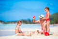 Family making sand castle at tropical white beach. Father and two girls playing with sand on tropical beach Royalty Free Stock Photo