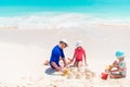 Father and little daughters making sand castle at tropical beach Royalty Free Stock Photo