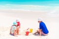 Father and little daughters making sand castle at tropical beach Royalty Free Stock Photo