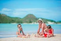 Family making sand castle at tropical white beach. Father and two girls playing with sand on tropical beach Royalty Free Stock Photo