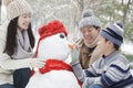 Family making snowman in a park in winter