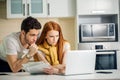 Family managing budget, reviewing their bank accounts using laptop in kitchen Royalty Free Stock Photo