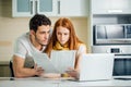 Family managing budget, reviewing their bank accounts using laptop in kitchen Royalty Free Stock Photo