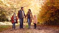 Family With Mature Parents And Two Children Holding Hands Walking Along Track In Autumn Countryside Royalty Free Stock Photo