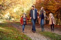 Family With Mature Parents And Two Children Holding Hands Walking Along Track In Autumn Countryside Royalty Free Stock Photo