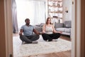 Couple practicing meditation exercises on the floor while sitting at the lotus pose