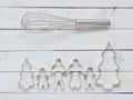 Family metal cookie or biscuit cutter composed of father, mother, brother, sister and pine tree with metal whisk over rough white