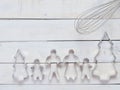 Family metal cookie or biscuit cutter composed of father, mother, brother, sister and pine tree with metal whisk over rough white