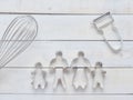 Family metal cookie or biscuit cutter composed of father, mother, brother, sister and pine tree with metal whisk and peeler over r