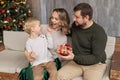 Family mom, dad and little son are sitting on the sofa and having fun, dad is holding a Christmas present Royalty Free Stock Photo