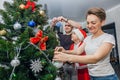 Family mom, dad and son in Santa costume decorate the Christmas tree with balloons in their apartment Royalty Free Stock Photo