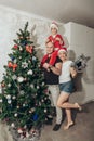 Family mom, dad and son in Santa costume fool around and play near the Christmas tree in their apartment Royalty Free Stock Photo