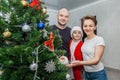 Family mom, dad and son in Santa costume posing near the Christmas tree in their apartment Royalty Free Stock Photo