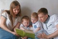 Family mom, dad and two twin brothers read books laying on the bed. Family reading time. Royalty Free Stock Photo