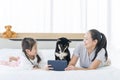 A family with a mom and daughter using a tablet in bed in the bedroom with a Shiba Inu. Girl and Dog looking at tablet Royalty Free Stock Photo