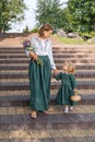 Family mom with daughter in vintage retro linen dresses with bouquet of flowers walking dawn a stairs in a park garden