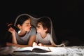 Family Mom and little son reading a book with a flashlight under the blanket Royalty Free Stock Photo