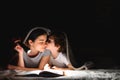 Family Mom and little son reading a book with a flashlight under the blanket Royalty Free Stock Photo