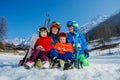 Family of mom and small kids sit with ski in snow over mountain Royalty Free Stock Photo