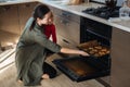 Family, Mom with toddler baby girl cooking gingerbread and puts cookies in oven. Christmas homemade gingerbread biscuit Royalty Free Stock Photo