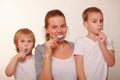 Mom and two blond boys brush their teeth