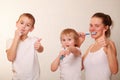 Mom and two blond boys brush their teeth