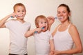 Mom and two blond boys brush their teeth