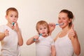 Mom and two blond boys brush their teeth