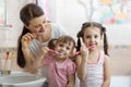 Family mom and two little girls brush their teeth