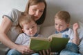 Family mom and two twin brothers toddlers read books laying on the bed. Family reading time. Royalty Free Stock Photo