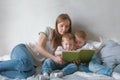 Family mom and two twin brothers toddlers read books laying on the bed. Family reading time. Royalty Free Stock Photo
