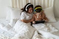 Family morning in bedroom: mom in headphones look at little kid son play games on tablet computer Royalty Free Stock Photo