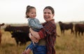Family, mother and baby on a farm with cows in the background eating grass, sustainability and agriculture. Happy Royalty Free Stock Photo