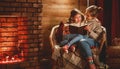 Family mother and child reading book and drink tea on winter evening by fireplace Royalty Free Stock Photo