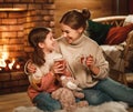 Family mother and child reading book and drink tea on winter evening by fireplace Royalty Free Stock Photo