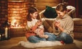 Family mother and child reading book and drink tea on winter evening by fireplace Royalty Free Stock Photo