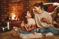 Family mother and child reading book and drink tea on winter evening by fireplace Royalty Free Stock Photo