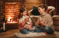 Family mother and child reading book and drink tea on winter evening by fireplace Royalty Free Stock Photo