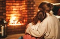 Family mother and child reading book and drink tea on winter evening by fireplace Royalty Free Stock Photo